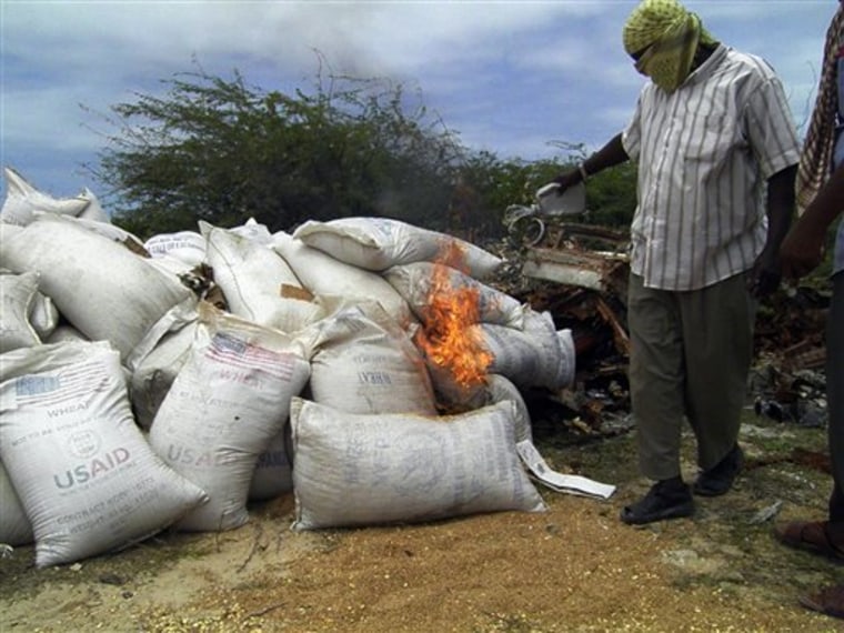 Al Shabab man burns white bags of wheat bearing an American flag and the stamp USAID in Mogadishu on Friday. Islamist fighters in Somalia said Friday that they seized food from the World Food Program from markets in Mogadishu and burned more than 500 bags of maize and wheat. 